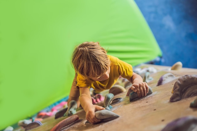 Ragazzino che si arrampica su una parete rocciosa con stivali speciali per interni