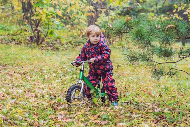 Ragazzino che si diverte in bicicletta nella foresta autunnale. Messa a fuoco selettiva sul ragazzo