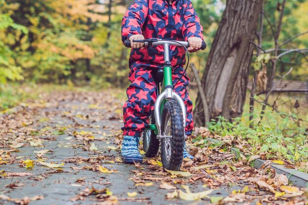 Ragazzino che si diverte in bicicletta nella foresta autunnale. Messa a fuoco selettiva sul ragazzo