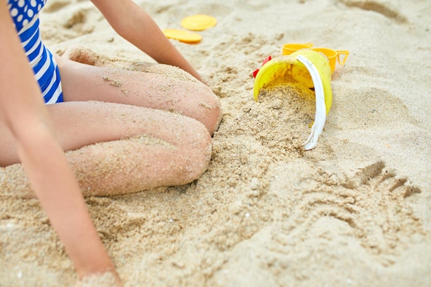 Ragazzino che si diverte sulla spiaggia e gioca con i giocattoli di sabbia