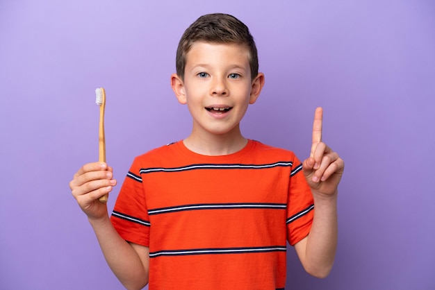 Ragazzino che si lava i denti isolato su sfondo viola che punta verso l'alto una grande idea