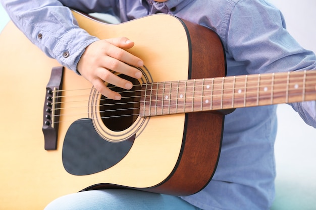 Ragazzino che suona la chitarra a casa, primo piano