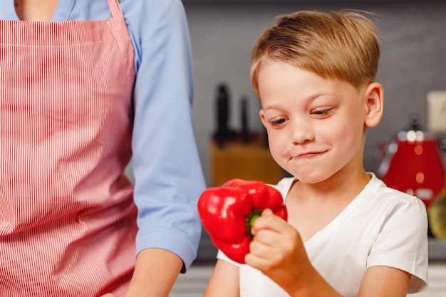 Ragazzino che tiene peperone rosso in cucina