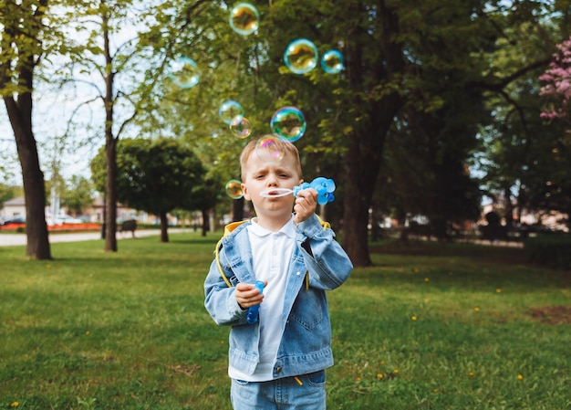 Ragazzino con bolle di sapone nel parco giochi attivi di giornata di sole primaverile per bambini