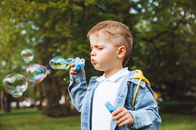 Ragazzino con bolle di sapone nel parco giochi attivi di giornata di sole primaverile per bambini