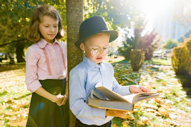 Ragazzino con cappello, occhiali, libro di lettura e ragazza