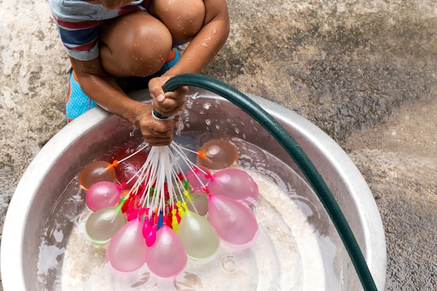 Ragazzino con il tubo flessibile dell'acqua che riempie le mongolfiere variopinte