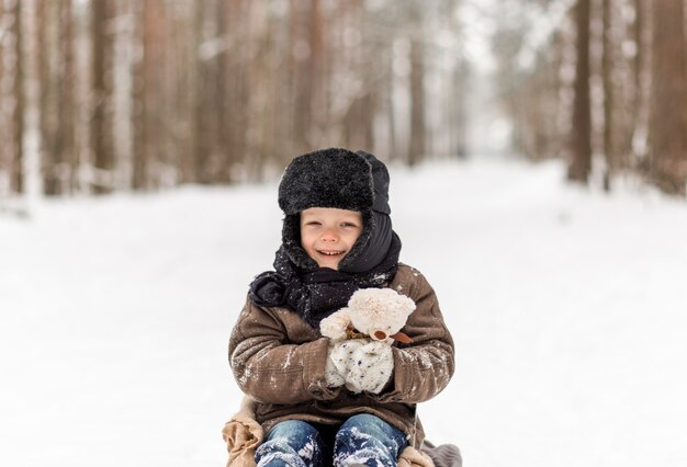 Ragazzino con la slitta nella foresta di inverno