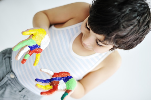 Ragazzino con le mani dipinte in vernici colorate pronte per le stampe a mano