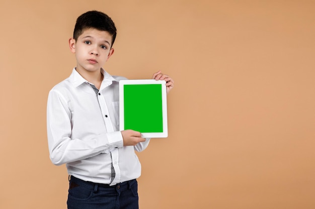 Ragazzino con un tablet sullo sfondo giallo chiaro dello studio