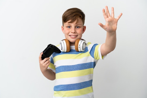 Ragazzino dai capelli rossi che tiene in mano un game pad isolato su sfondo bianco contando cinque con le dita