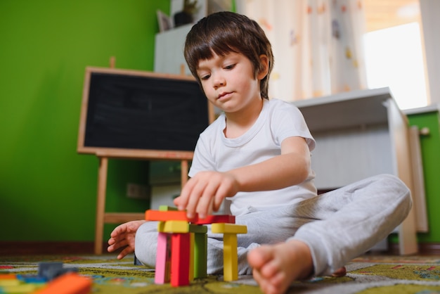 Ragazzino del bambino che gioca con i giocattoli di cubi di legno nella scuola materna a casa o nell'asilo nido