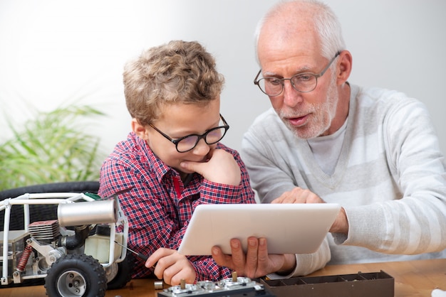 Ragazzino del figlio e del nonno che ripara l'automobile radiocomandata di modello a casa