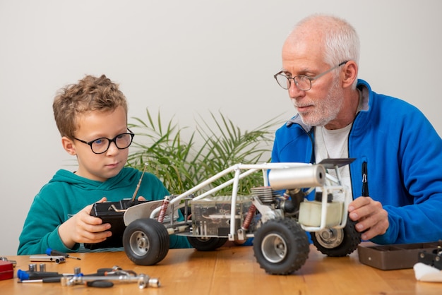 Ragazzino del figlio e del nonno che ripara l'automobile radiocomandata di modello a casa