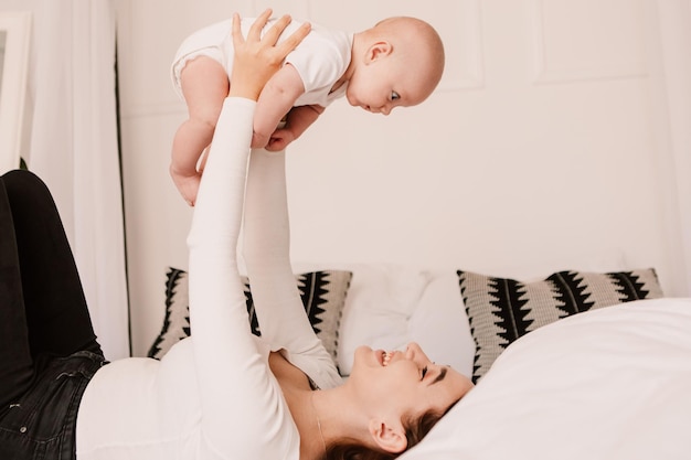 Ragazzino divertente bambino carino, la madre tiene a giocare con il figlio, lancia il bambino. Ridere sorridente giocoso