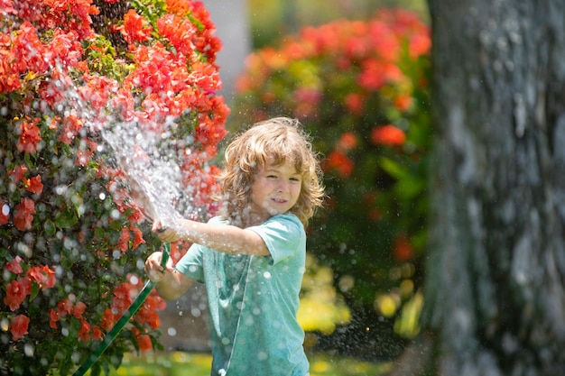 Ragazzino divertente che gioca con il tubo da giardino nel cortile Bambino che si diverte con spruzzi d'acqua Estate ou