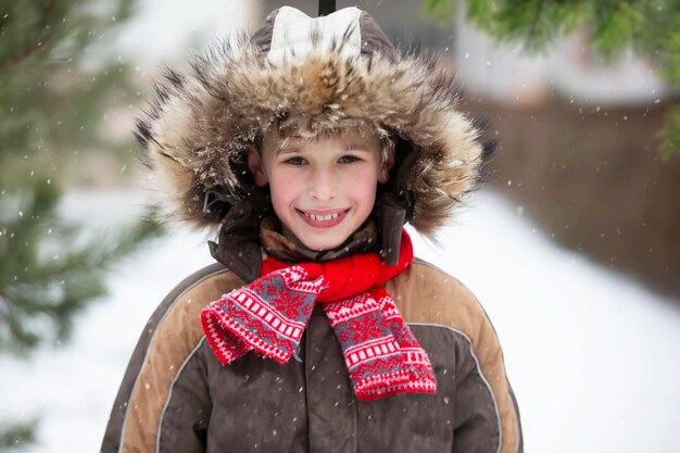 Ragazzino divertente tra gli alberi di Natale innevati Bambino in inverno