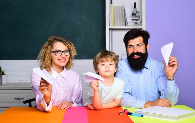 Ragazzino e i suoi genitori con aeroplano di carta origami lezione concetto di educazione famiglia felice