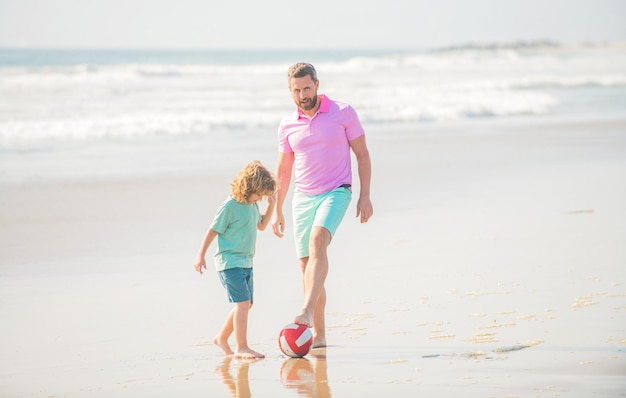 Ragazzino e papà che corrono sulla spiaggia durante le vacanze estive con il pallone da calcio