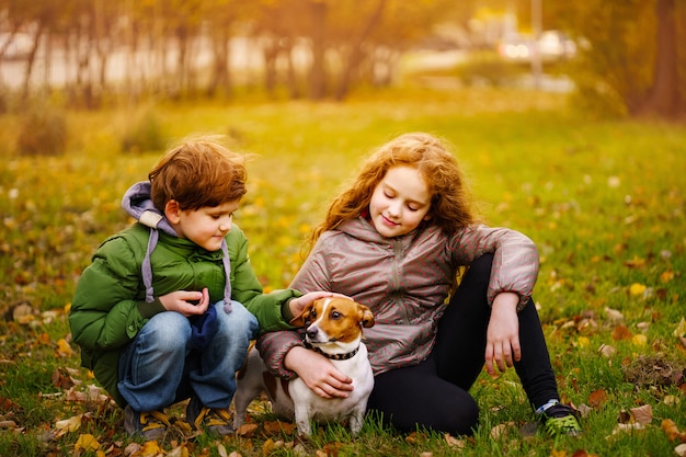 Ragazzino e ragazza con il suo cucciolo jack russell in autunno all&#39;aperto.