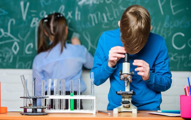 Ragazzino e ragazza in laboratorio esperimenti di biologia con microscopio Ragazzini che guadagnano chimica nel laboratorio scolastico Chimica scienza Bambini piccoli Scienza Godersi la vita universitaria