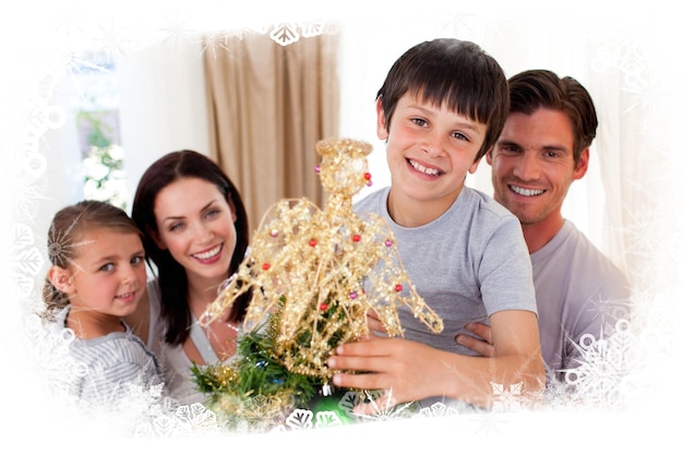 Ragazzino felice che decora un albero di Natale con la sua famiglia contro la cornice del gelo