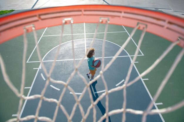 Ragazzino felice che gioca a basket nel parco giochi