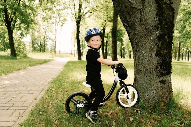 Ragazzino felice che guida una bici che corre nel parco