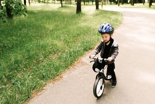 Ragazzino felice che guida una bici che corre nel parco