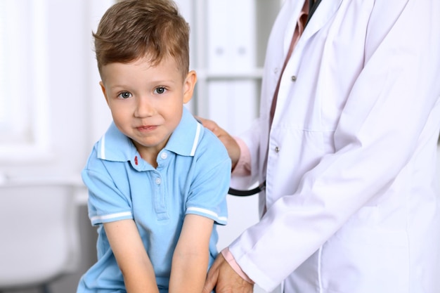 Ragazzino felice che si diverte mentre viene esaminato dal medico con uno stetoscopio Assicurazione sanitaria e concetto di aiuto