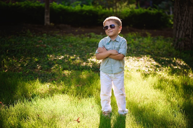 Ragazzino felice con gli occhiali da sole in giardino.