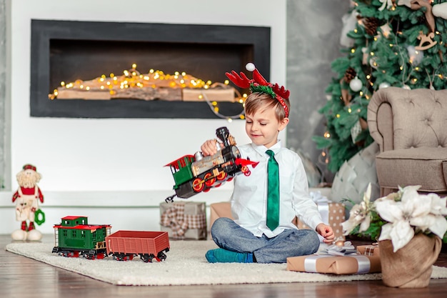 Ragazzino felice con un trenino regalo sotto l'albero di Natale la mattina di Capodanno