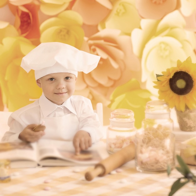 Ragazzino felice con uno chef di libro che prepara la colazione nel kit