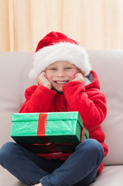 Ragazzino festivo che sorride alla macchina fotografica con il regalo