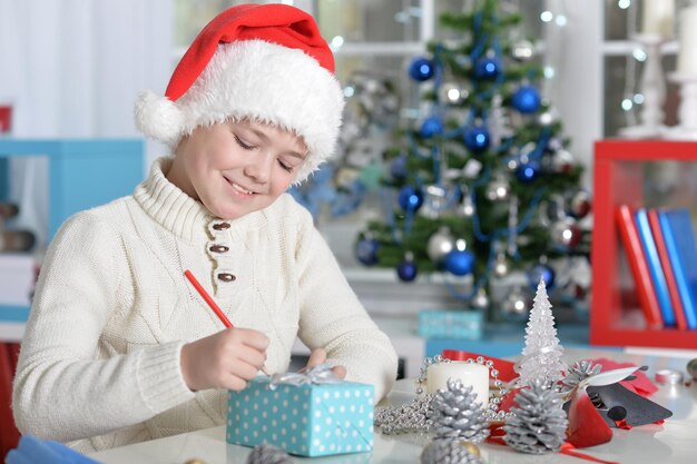 Ragazzino in cappello di Babbo Natale che scrive lettera