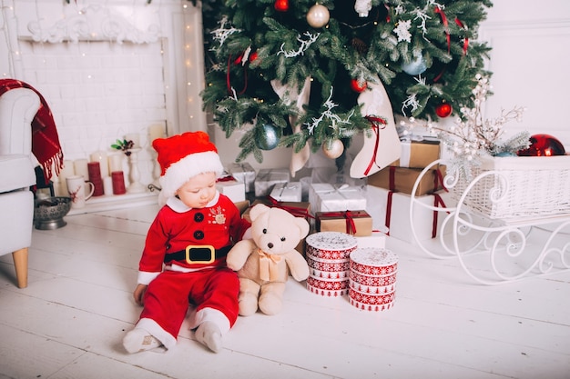 Ragazzino in costume di Babbo Natale in interni chiari