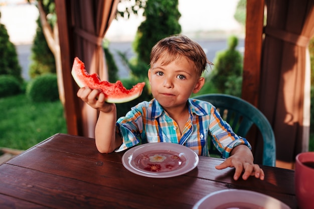 Ragazzino in età prescolare che mangia anguria all'aperto nel villaggio