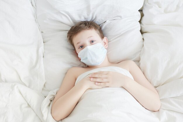 Ragazzino in maschera Concetto epidemico Coronavirus Kid a letto