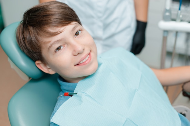 Ragazzino in poltrona odontoiatrica. Paziente presso l'ufficio del dentista dopo il trattamento.