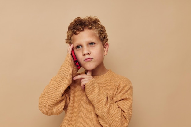 Ragazzino in un maglione che parla al telefono