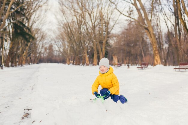 Ragazzino in una passeggiata nel parco con la sua famiglia in inverno, divertendosi e godersi la neve