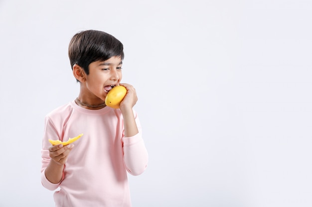 Ragazzino indiano / asiatico che mangia mango