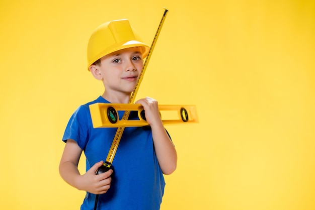 Ragazzino nel costruttore di casco giallo con strumento di livello.