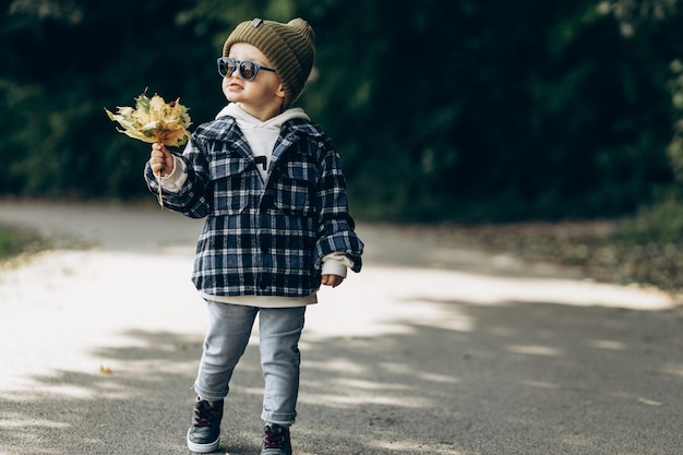 Ragazzino nel parco che tiene le foglie di autunno