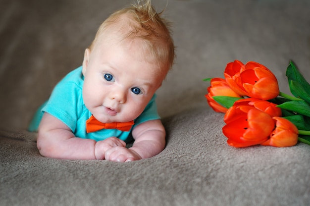 Ragazzino sdraiato sul letto e bouquet di tulipani