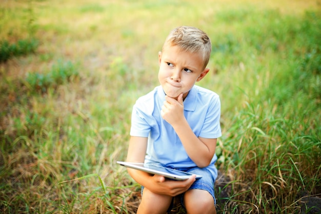 Ragazzino seduto nel cortile e giocare su tablet pc.