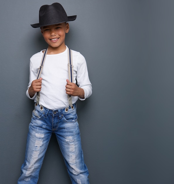 Ragazzino sorridente con cappello nero e bretelle