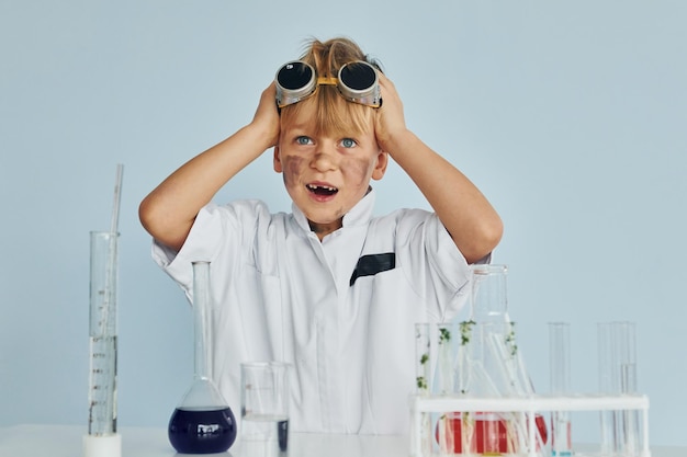 Ragazzino spaventato in cappotto che interpreta uno scienziato in laboratorio utilizzando l'attrezzatura