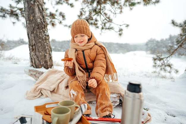 Ragazzino su un picnic nella foresta invernale