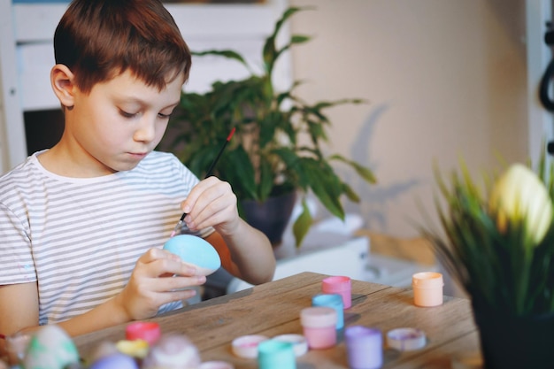 Ragazzino sveglio che colora le uova per pasqua